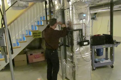 NIST technician installing monitoring instruments on heat pump equipment, 2013